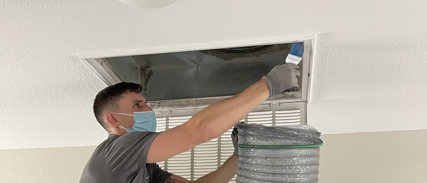 Unified Air Duct technician cleaning inside an air vent register connected to duct cleaning equipment in a Las Vegas home
